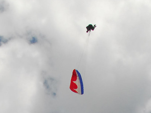 Piloto passa sobre o parapente vermelho durante um Looping