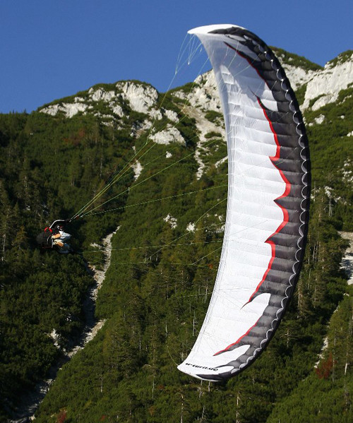 Parapente branco em rolagem lateral com paisagem alpina ao fundo